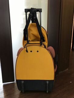 Желтый туристический чемодан на колесиках и рюкзак